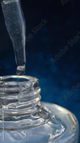 Glass pipette with facial serum on a light background. Essential oil close-up in a pipette. A skin care product with hyaluronic acid in a pipette.