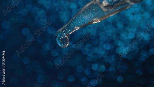 Glass pipette with facial serum on a light background. Essential oil close-up in a pipette. A skin care product with hyaluronic acid in a pipette.