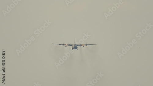 Military aircraft performs a graceful landing amidst atmospheric conditions