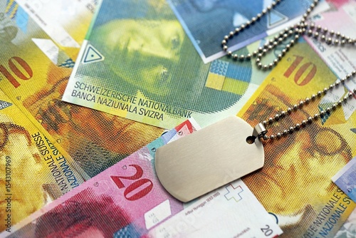 Swiss franc banknotes and military token. The current francs money bills and dogtags lies on table in big amount. The concept of army service in Switzerland