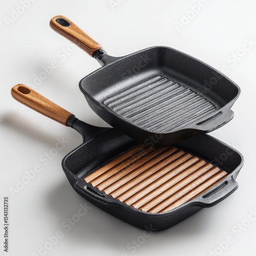Two square cast iron grill pans, one stacked atop the other, featuring wooden handles