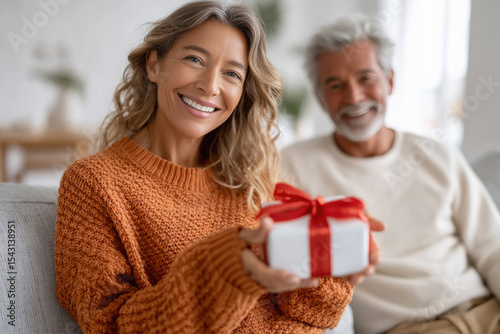 young beautiful woman holding gift box at home photo