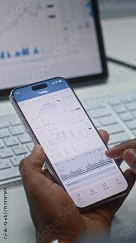 African American Stock Trader Analyzing Real-Time Stocks, Exchange Market Charts on Smartphone and Tablet Computer Using Online Trading App. Investment Agent Working in Office. Close Up. Vertical Shot