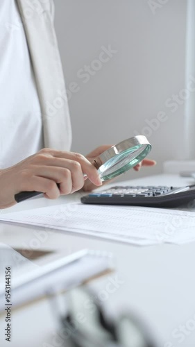 Financial professional analyzing company reports with magnifying glass, checking detailed metrics and verifying accounting precision on desk workspace. Audit and taxes in business