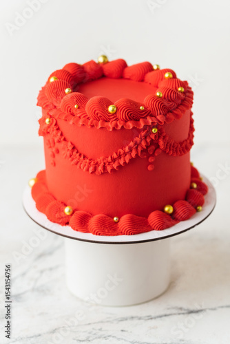 Foto Delicate lambeth style birthday cake with red cream cheese frosting decorated with cream tracery and golden sprinkles