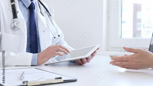 Doctor man showing information on tablet to patient woman during medical visit, explaining diagnosis and treatment options, providing medical consultation using modern technology. Medicine concept