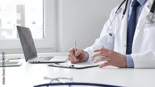 Male doctor writing a prescription and filling out medical records on a clipboard in an office setting, showcasing the essential aspects of healthcare and patient care. Medicine and health care