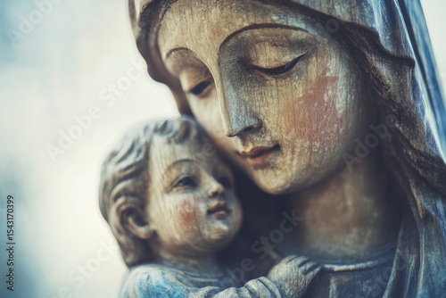Weathered statue of Mary cradling baby Jesus, depicting motherly love and faith.