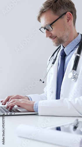 Middle aged doctor man is diligently typing on a laptop, likely updating patient records or conducting research, showcasing the intersection of healthcare and technology in medical setting. Medicine