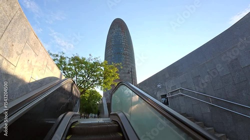 Sunrise illuminating torre glories in barcelona, seen from street level with escalators
