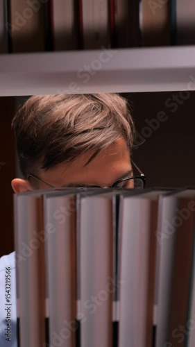 vertical video Student searching for book on library shelf