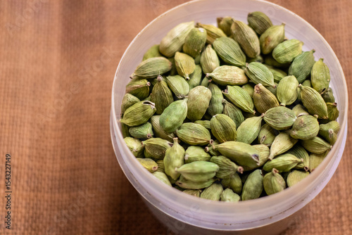 A bowl of fresh green cardamom seeds arranged on a table for use or display