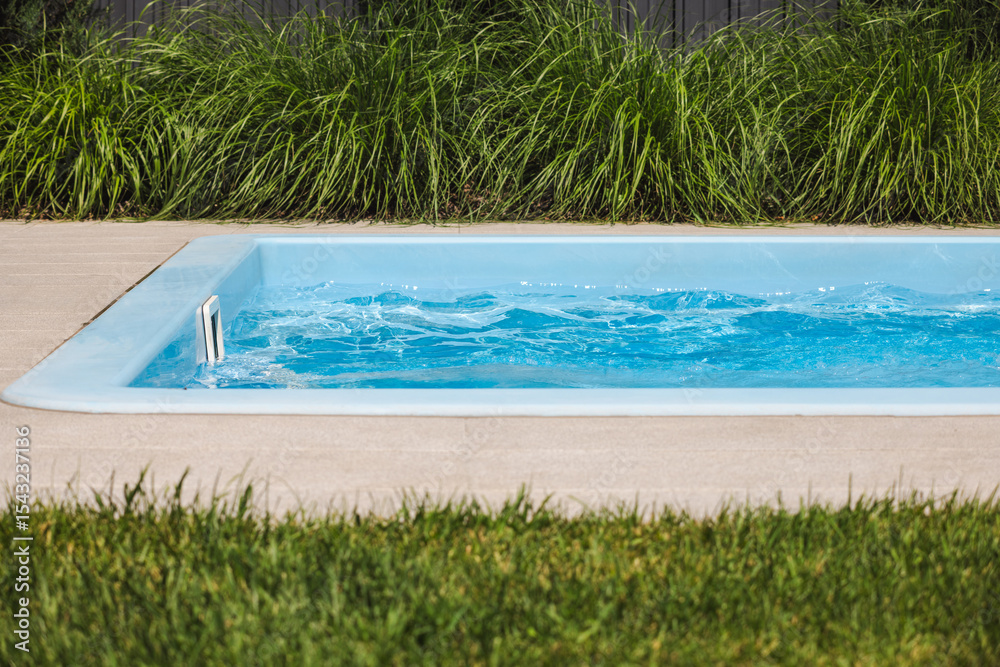 Obraz premium Empty backyard pool with active counter-current system generating waves near skimmer
