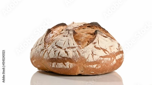A loaf of bread on a white background is browned on top and covered with flour