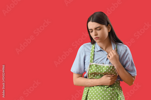 Young housewife having heart attack on red background