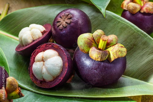 Mangosteen fruits on green leaves close up.