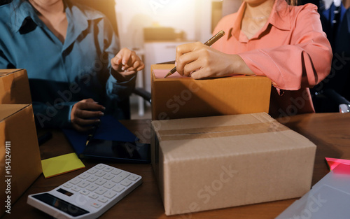 Startup SME small business entrepreneur of freelance Asian woman wearing apron using laptop and box to receive and review orders online to prepare to pack sell to customers, online sme business ideas.