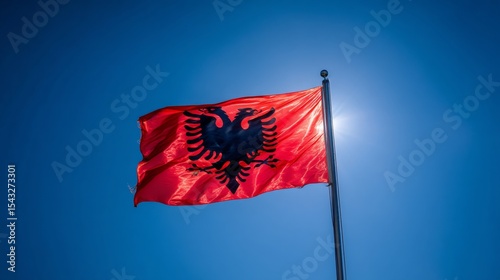 Albanian flag waving proudly against a clear blue sky during a sunny day