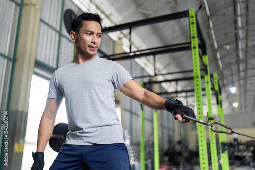 Strength Training. Man performing cable exercise at gym for upper body workout.