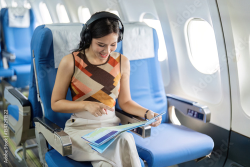 Excited Traveler Planning Trip with Map on Airplane. Woman engaged in travel exploration during flight.