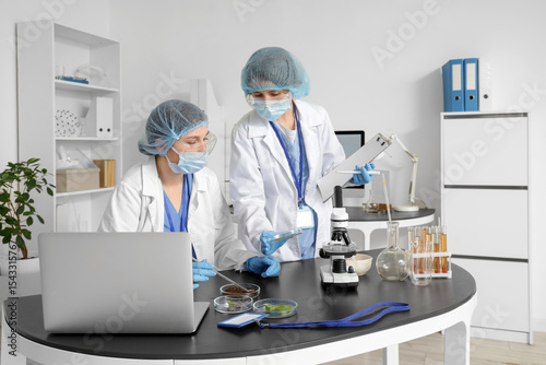 Female scientists working with Petri dishes at table in laboratory