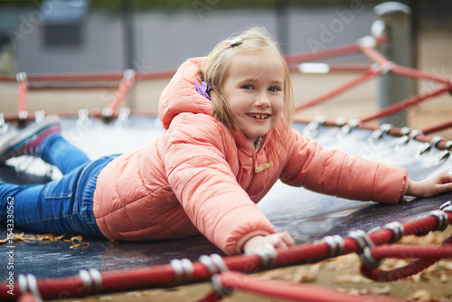 Cheerful little girl having fun on playground in autumn park in Paris, France.