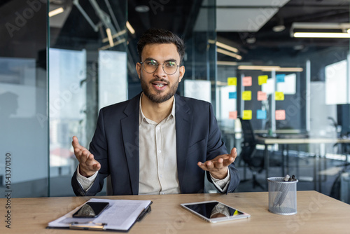 Foto A businessman in a suit is on a video call, looking directly at the camera and g