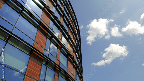 Modern glass and wood office building against blue sky. Curved facade features reflective windows and wooden panels. Contemporary urban architecture and innovative eco-friendly design aesthetics.