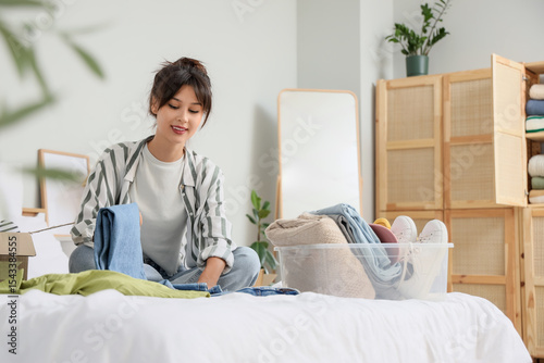 Young woman packing jeans f...