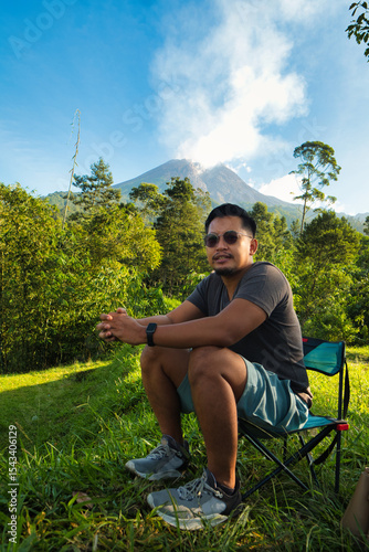 Man Relaxing Outdoors With Scenic Merapi Mountain and Lush Greenery in the Background