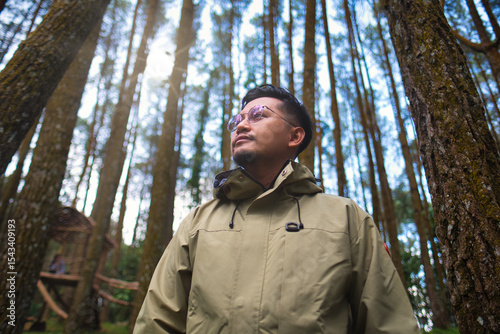 Man in Nature Standing Among Tall Trees in Outdoor Woodland Area
