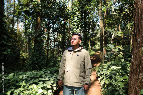 Man Wearing Jacket in Lush Forest Environment Under Sunlight
