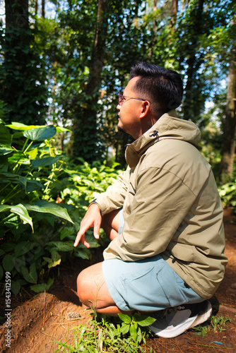 Man Exploring Greenery in a Lush Forest During a Sunny Day