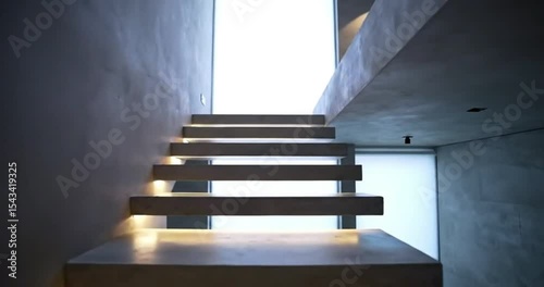 A light-filled, empty interior stairway with wooden steps leads upward, a modern design element in a spacious home