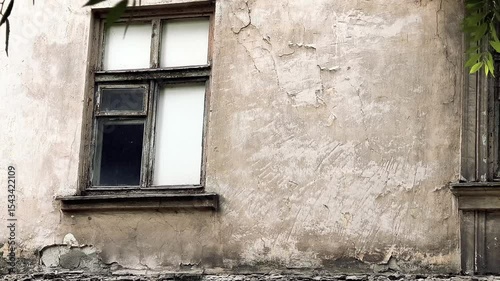 old window in a dilapidated house. old broken wooden window in the wall. wall of a house with cracks. abandoned house.