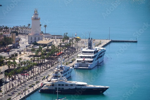 view from Mirador de Gibralfaro to the harbor with the promenade with luxury yachts and the lighthouse La Farola de Málaga, Costa del Sol