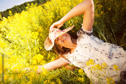 Happy joyful girl lies among yellow flowers in a field.