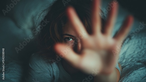 A woman is holding her hand up in front of her face, blocking her view
