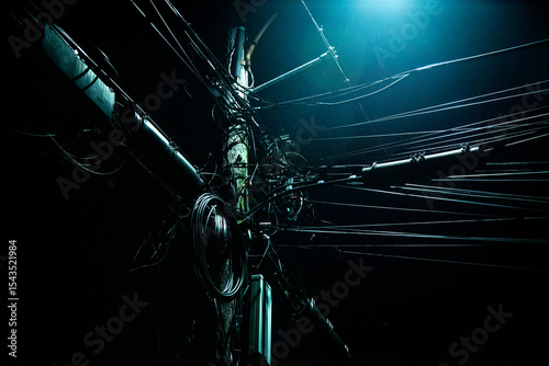 Dark telephone pole with many wires
