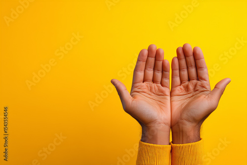 Open Hands Showing Palms Up Against A Bright Yellow Background