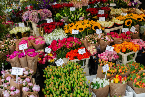 A dense display of assorted fresh cut flowers and bouquets for sale at a vibrant flower market stall