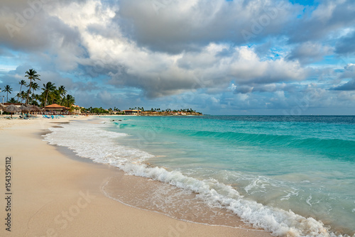 The idyllic beauty of Divi Beach, Aruba, with its gentle waves, swaying palm trees, and inviting resorts.