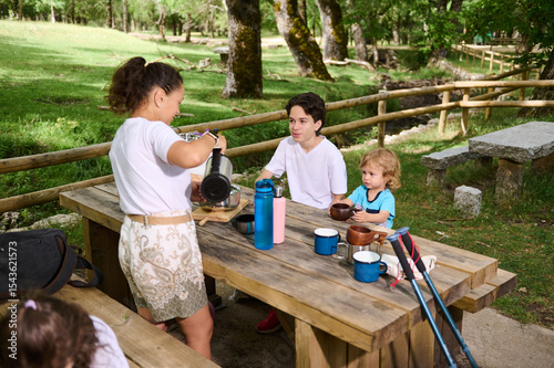 Family Enjoying a Picnic at a Park Table in a Scenic Outdoor Setting