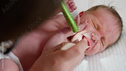A doctor examines a newborn in a clinic, potentially using ultraviolet light as part of a medical procedure.