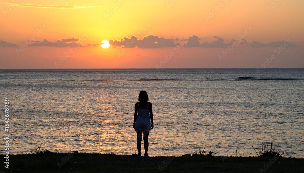 Fototapeta premium 黄金色に染まる夕暮れ時、砂の岬の端に立つ人影が静かな沖縄の海を見つめる。暖かな夏の夕焼け空が燃え上がり、心に響く穏やかで反射的な静寂の時間が広がる情景