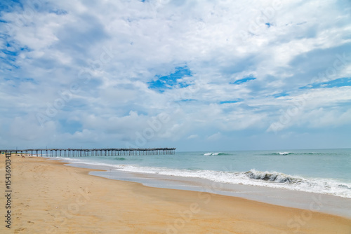 Wooden Pier over Atlantic Ocean. Scenic beach view with clouds and surf.