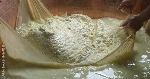 Cinematic Super slow motion close up of artisan cheesemakers working on traditional Italian Parmesan cheese Parmigiano Reggiano making process at cheese production creamery dairy factory at 1000 fps.