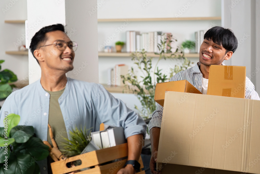 Joyful gay couple unpacking boxes and sharing smiles in their new home Joyful gay couple unpacking boxes and sharing smiles in their new home