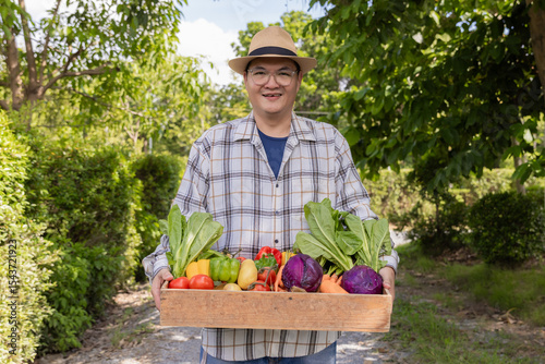Farmer holding wooden box full of fresh vegetables. Basket with vegetable. Man holding big box with different fresh farm vegetables.