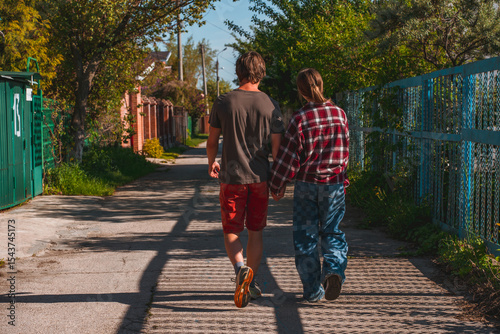 A young couple on a date walks along a rural street in the summer, a boy with a girl